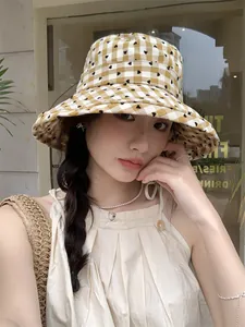 Detail view of model wearing a stylish yellow heart checkered bucket hat outdoors