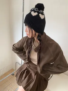 Side view of a vintage black knit beanie featuring white heart patterns and a pom-pom