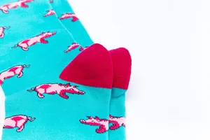 Close-up of vibrant turquoise socks with pink pig patterns and magenta heel details.