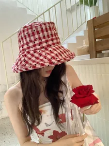 Detailed close-up of a red and white checkered heart pattern bucket hat on a model