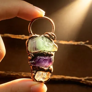 Close-up of raw amethyst and fluorite pendant in rustic copper plating with light beams