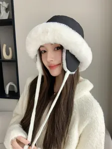 Close-up of a model wearing a stylish black and white plush winter hat with ear flaps