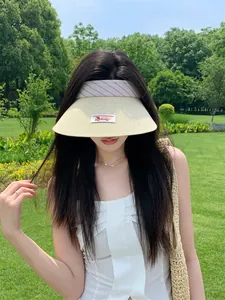 Vista dettagliata di una visiera in paglia beige con patch a forma di cane su modella
