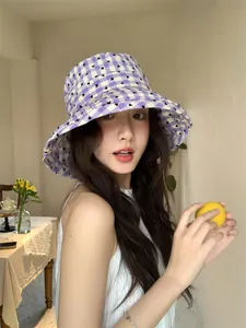 Model wearing a stylish purple checkered fisherman hat with heart patterns in a cafe.
