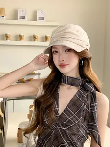 Détail d'une casquette gavroche en lin beige à plis portée par une femme dans un café