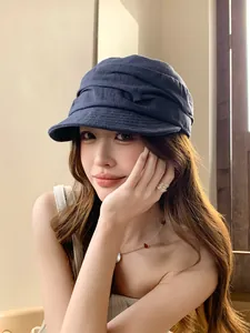 Détail d'une casquette gavroche en lin plissé bleu marine portée par un mannequin en studio