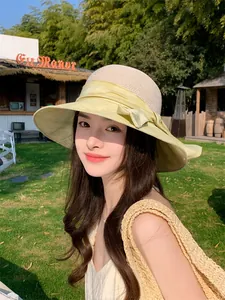 Détail d'un chapeau de paille pour femmes avec large bord et nœud papillon jaune.