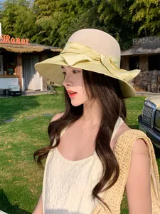 Modèle portant un chapeau de paille à larges bords avec nœud jaune sur fond de ranch ensoleillé
