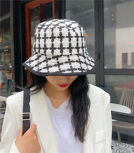 Close-up view of a stylish retro black and white checkered knit bucket hat on a model
