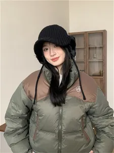 Close-up of a stylish black knit winter earflap hat worn by a model in an indoor setting