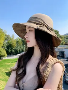 Détail d'un chapeau de soleil en paille à large bord pour femme avec nœud décoratif.