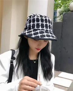 Close-up of a stylish black and white checkered knit bucket hat on an Asian model.