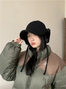 Detailed view of women's black knitted winter hat with protective brim and cozy ear flaps