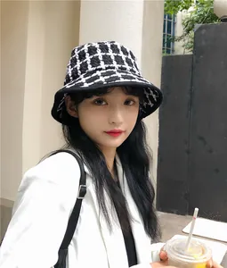 Detail of a retro black and white checkered knitted bucket hat worn by a model