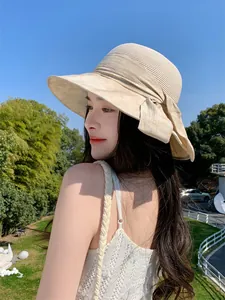 Vue de côté d'une femme portant un chapeau de paille élégant avec un grand nœud au soleil