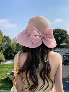 Elegant pink Hepburn-style straw sun hat featuring a large organza bow detail from the back
