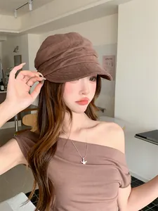 Vue détaillée d'un béret en lin plissé marron porté par un mannequin dans un café chic