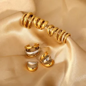Detailed view of assorted stainless steel C-shape ear cuffs on golden satin fabric.