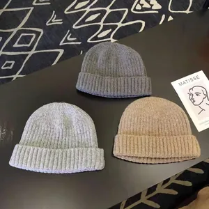 Close-up of three knitted skull caps in gray and beige tones for winter