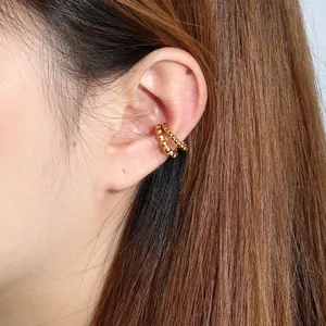 Close-up detail of a minimalist gold beaded stainless steel C-shaped ear cuff on female ear