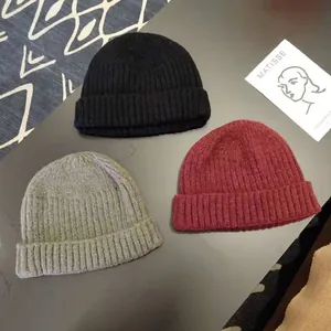 Detailed view of three warm winter knitted beanies in black grey and burgundy colors