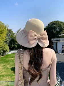 Detail view of a retro wide-brim straw hat featuring a large organza bow decoration.