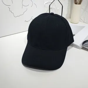 Minimalist view of a plain black adjustable baseball cap on a clean white table.