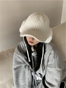 Detailed view of a stylish white thick knit earflap hat worn by a model in winter