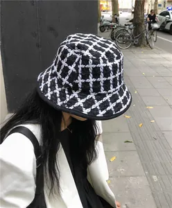 Close-up of a vintage black and white plaid knit bucket hat shown on a model outdoors
