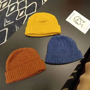 Detail of three knitted beanies in vibrant yellow, blue and brown colors for winter