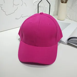 Detailed view of a bright fuchsia pink plain baseball cap on a minimalist white desk setup