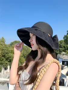 Detail of a black Audrey Hepburn style organza straw hat with a large bow for sun protection.