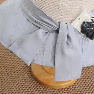 Gros plan détaillé du ruban gris sur un chapeau de paille à larges bords pour femmes