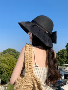 Back view of a woman wearing a black Hepburn style straw hat with an organza bow