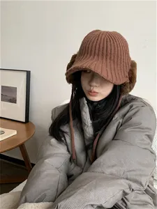 Close-up of a stylish brown knitted winter trapper hat with warm faux fur earflaps