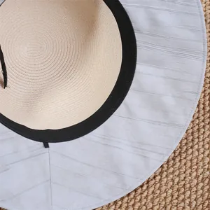 Gros plan d'un chapeau de soleil en paille à large bord, texture tissée et bord gris