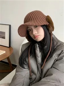 Woman wearing a stylish brown knit trapper hat with plush earmuffs for winter warmth