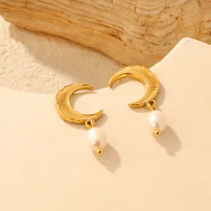 Detailed macro view of golden crescent moon earrings with elegant freshwater pearl drops
