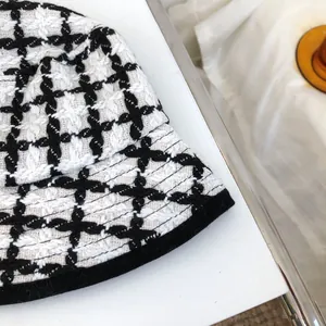 Close-up of vintage black and white checkered tweed bucket hat with textured woven fabric.