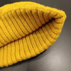 Close-up macro view of the yellow knitted winter beanie's warm ribbed texture details
