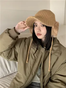 Detailed view of an Asian woman wearing a tan knit winter hat with plush ear flaps