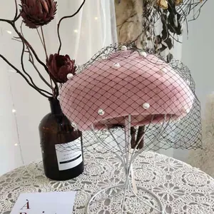 Close-up of pink wool beret featuring elegant black mesh veil and white pearls.
