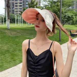 Frau mit großkrempigem, zweifarbigem Sonnenschutzvisier in einem sonnigen Park