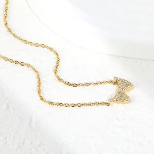 Detalle macro de un collar de lazo de acero dorado con circonitas brillantes