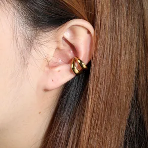 Close-up shot of a minimalist gold C-shaped stainless steel ear cuff worn on a model's ear