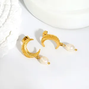 Detailed view of gold crescent moon earrings with freshwater pearl drops