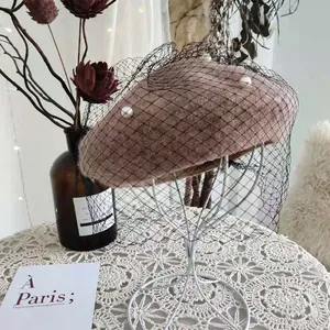 Detail of a vintage wool beret with black mesh veil and white pearls on a stand.