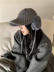 Close-up of a grey winter knitted hat with warm faux fur earflaps and a protective brim