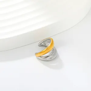 Detail shot of a two-tone gold and silver stainless steel C-shape ear cuff on a white prop