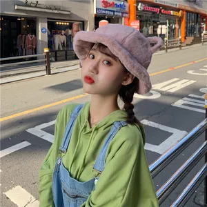 Close-up detail of a cute pink plush bucket hat with bear ears on a girl in a city street
